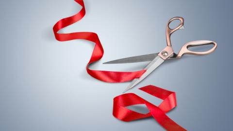 view of red ribbon having been cut by shiny scissors