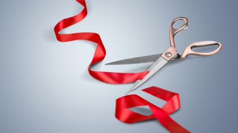 view of red ribbon having been cut by shiny scissors