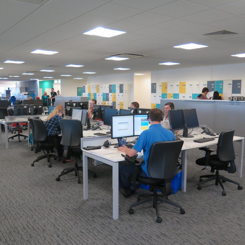 View of occupied banks of desks with coloured lockers beyond