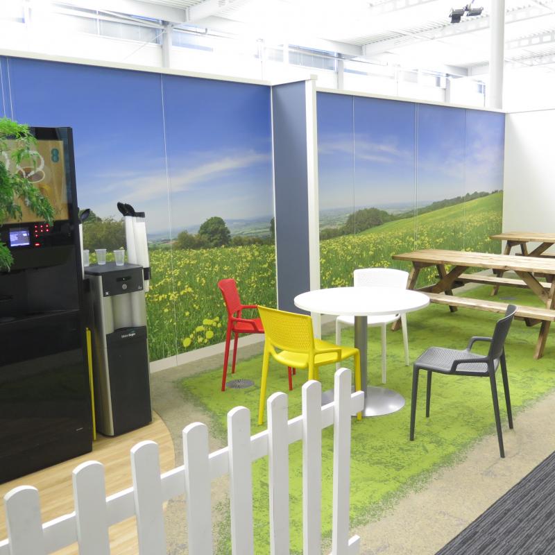 View of garden area with huge photograph of fields and sky behind vending machines