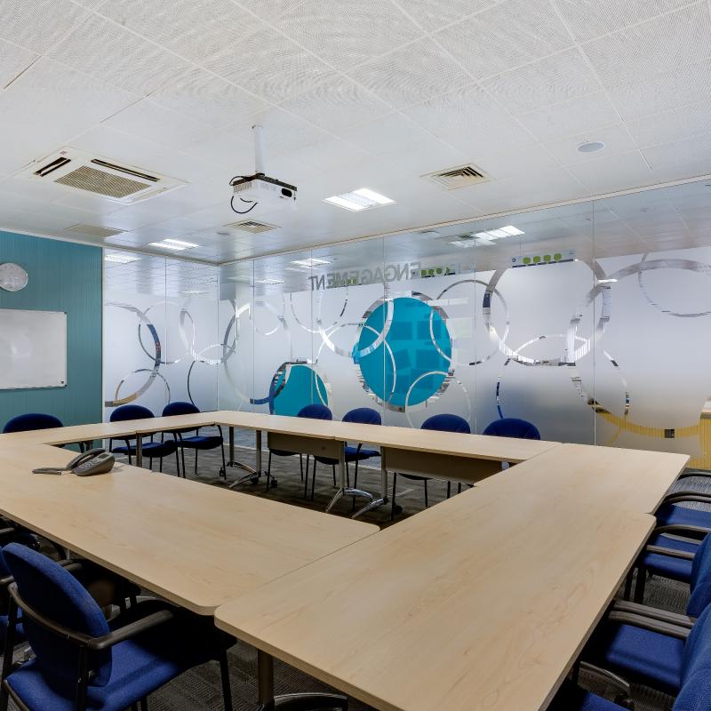 view of conference room with mobile tables set in square layout with 16 chairs, 4 on each side.