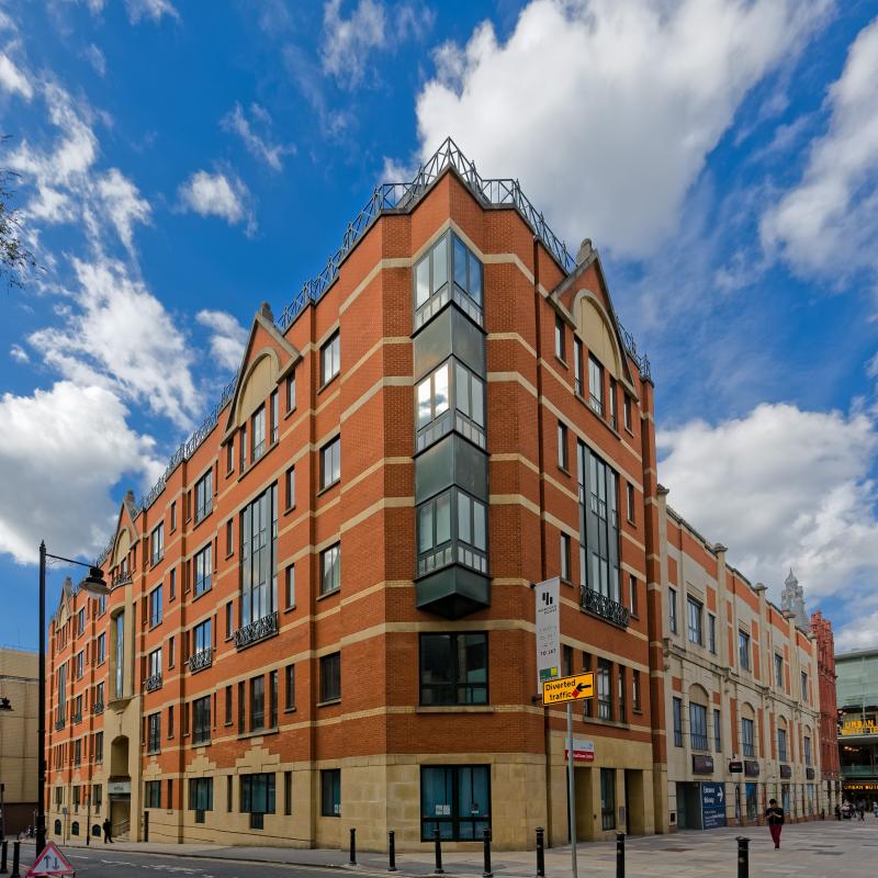 External view of 5 storey building showing mainly red brick with beige brick horizontal lines