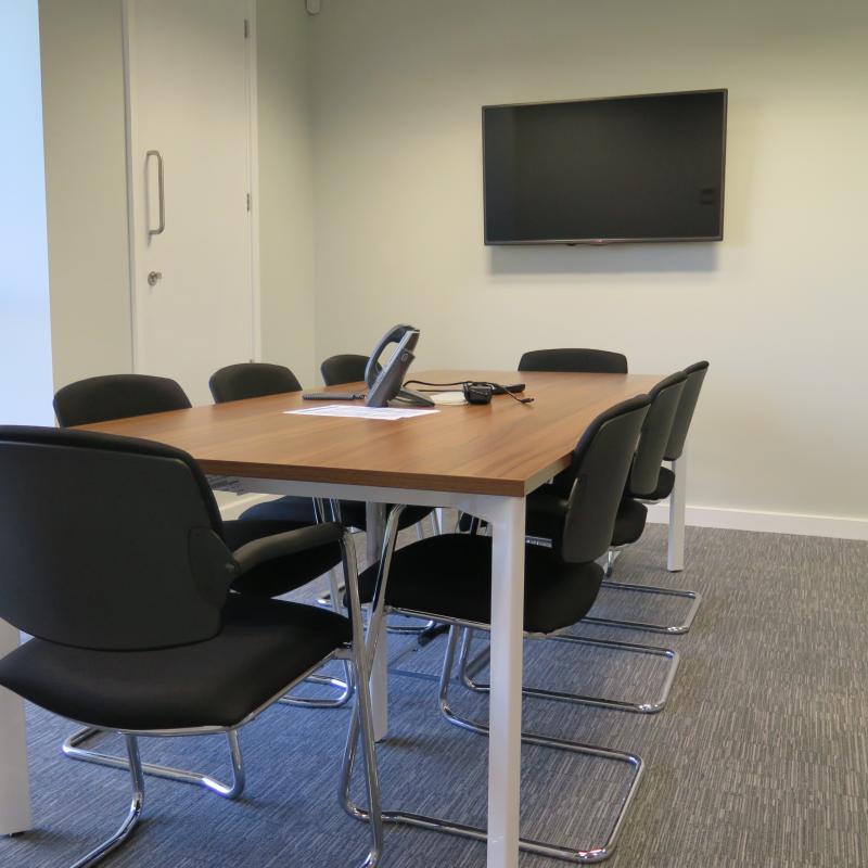 view of meeting room with table and chairs for 8 people and wall mounted TV